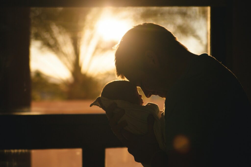 Man Carrying Baby Drawing Their Foreheads