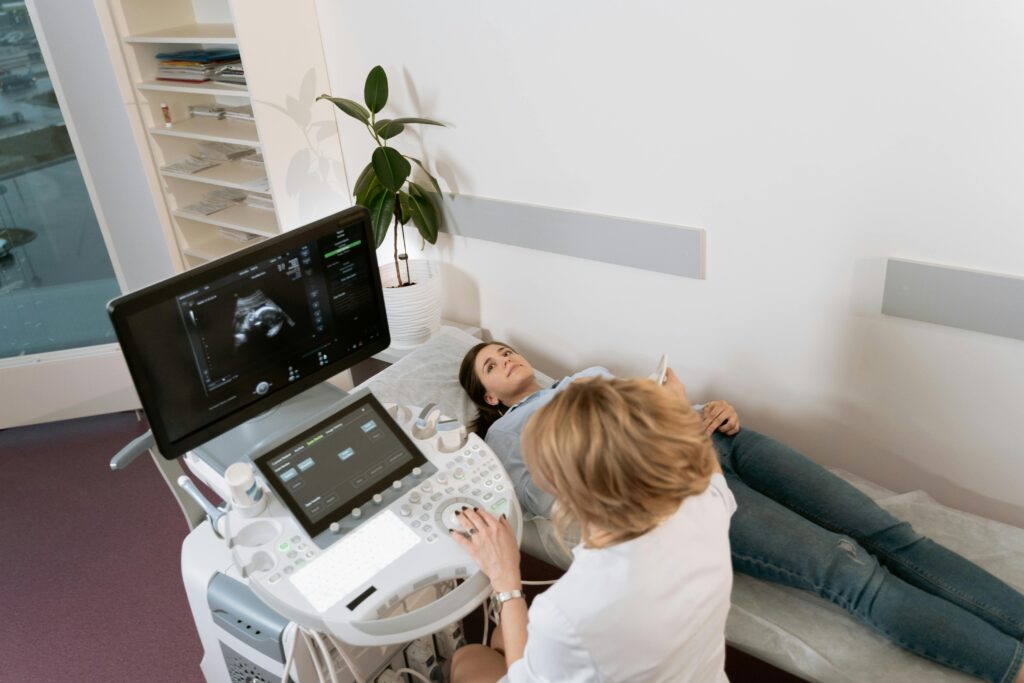 Pregnant woman receiving ultrasound consultation from medical professional in clinic.